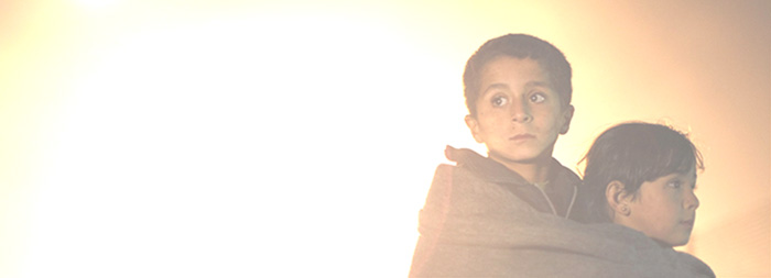 Syrian refugee children take shelter against the cold and fog shortly after arriving in Jordan early in the morning in November 2012. c UNHCR / B. Sokol.