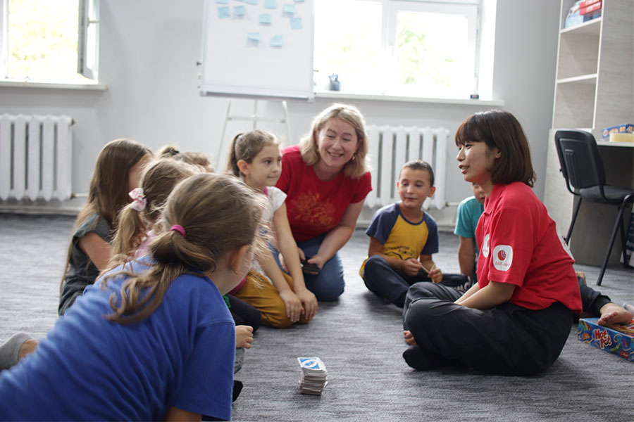 ウクライナ難民とホストコミュニティ住民の子ども双方が利用するチャイルドフレンドリーセンターにて子どもと話す平出職員。（2022年8月12日、AAR撮影）