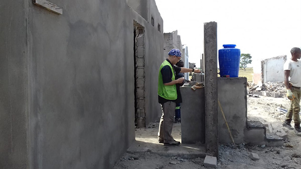 建設工事中のトイレにて手洗い場の蛇口を確認するGNJPスタッフ。ニャマタンダ中学校（ソファラ州ニャマタンダ郡、2019年6月29日撮影）