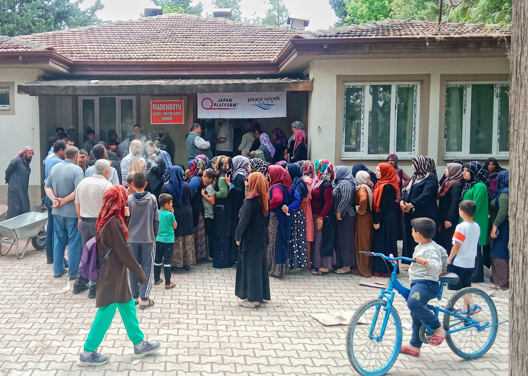 食料品と生活物資の配布を待つ地元住民の列。2023年5月12日、トルコ・ハタイ州アンタキヤ市マデンボユ村 ©PeaceWinds