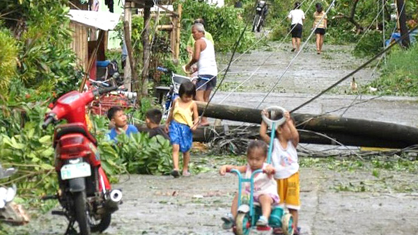 フィリピン中部パナイ島のパンダンにて。倒れた電柱、切れた電線の脇の子どもたち ©JAFS