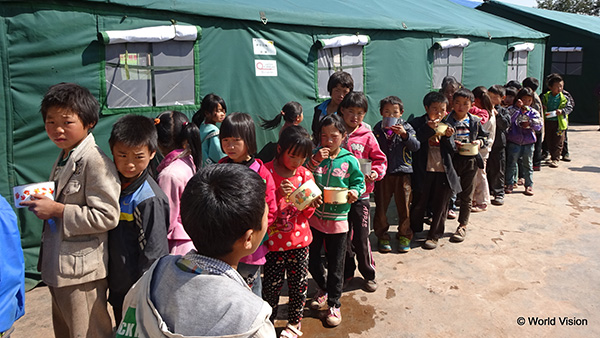 中国雲南省地震被災者支援2014 支援した教室用テント外観と給食の配膳に並ぶ児童