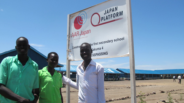 In front of the sign at a secondary school ©AAR