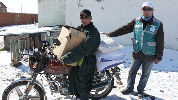 ザグ郡バイクで食糧を持ち帰る裨益者©ADRA