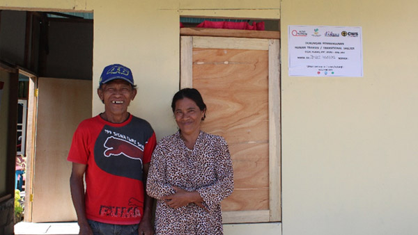 Family affected by the earthquake posing in front of the completed temporary housing ©CWS