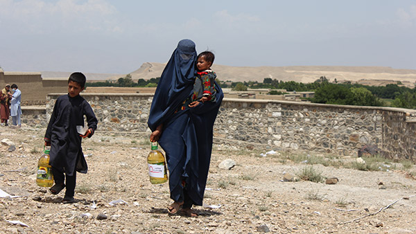 配布された食用油を運ぶ母親と子どもたち（2022年4月28日撮影）©JEN