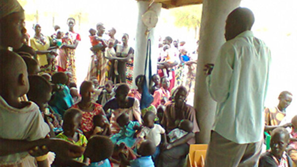 外来センターにて栄養診断を待つ親子と栄養不良について説明をする事業スタッフ（南スーダン）©Word Vision