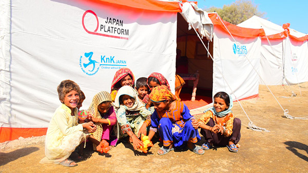 配布されたテントの前で笑顔を見せる子どもたち（シンド州）©KnK
