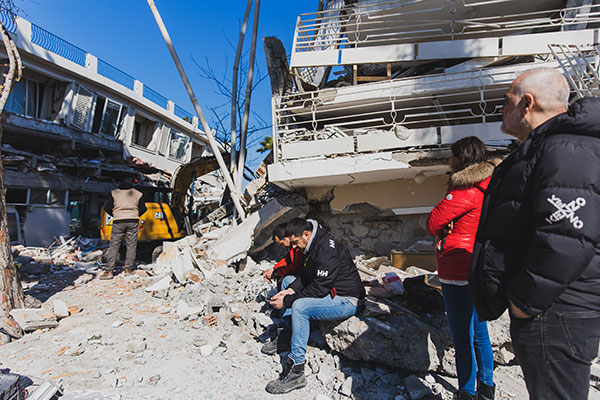 崩れた建物の前で座り込む行方不明者の家族（アルスズにて2月9日撮影）©PeaceWinds